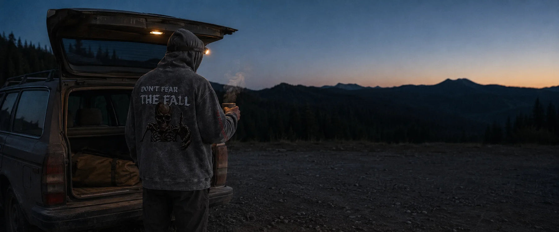 Climber in an Avila Climbing Co. Don't Fear The Fall hoodie at a tailgate camp at dusk, mountain ridgeline behind