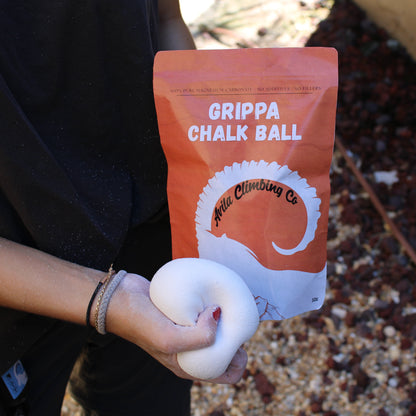 Person holding a grippa chalk ball with a branded packaging in an outdoor setting