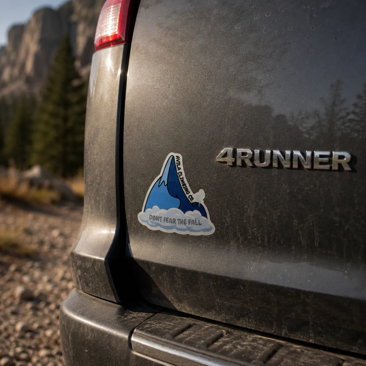 A die-cut vinyl sticker applied to the rear left side of a dark gray 4Runner vehicle, featuring a blue shark jumping out of water with the text 'DON'T FEAR THE FALL' and 'Avila Climbing Co' on the side.