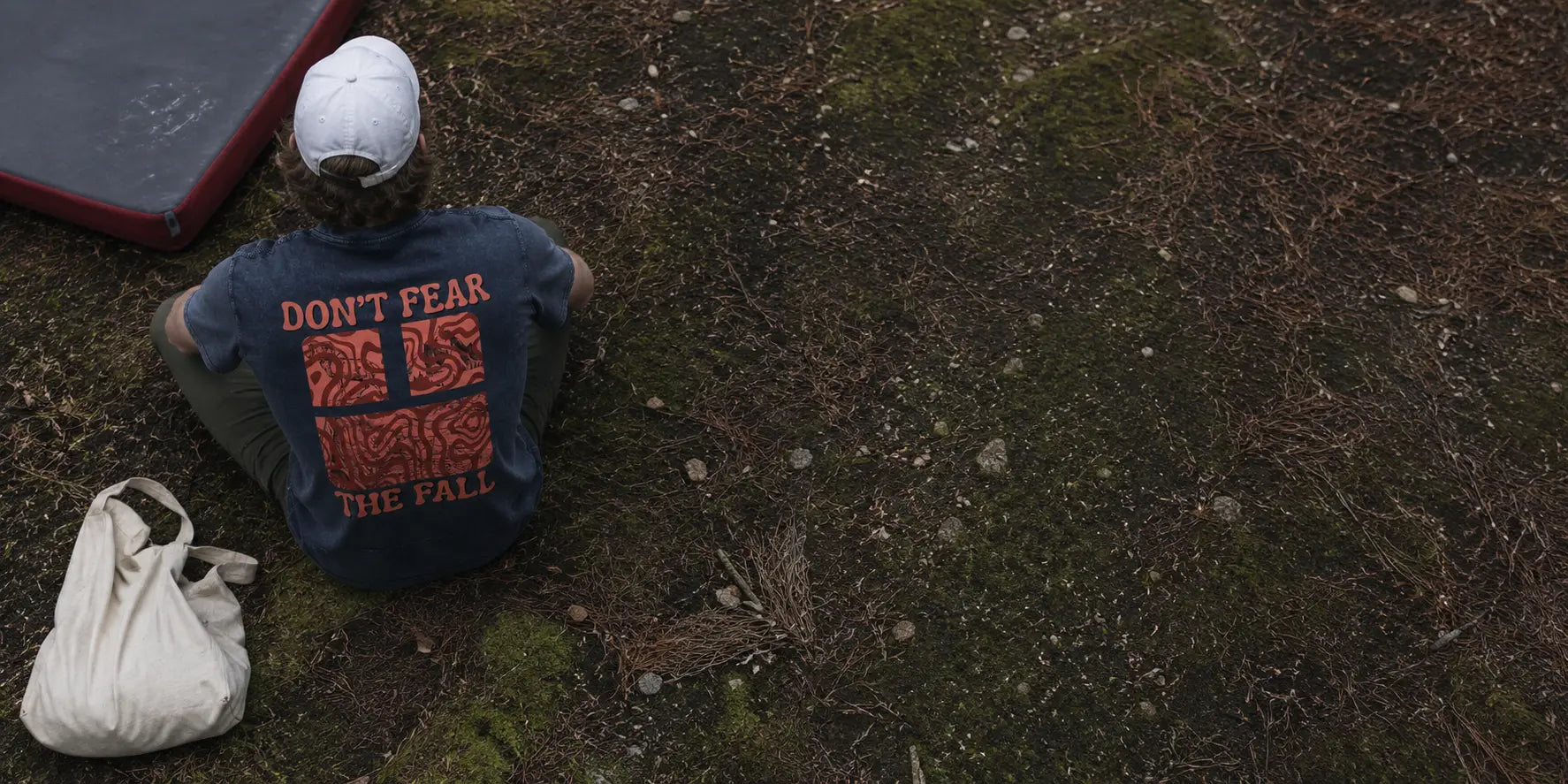 Person wearing a shirt with motivational text sitting on the ground.